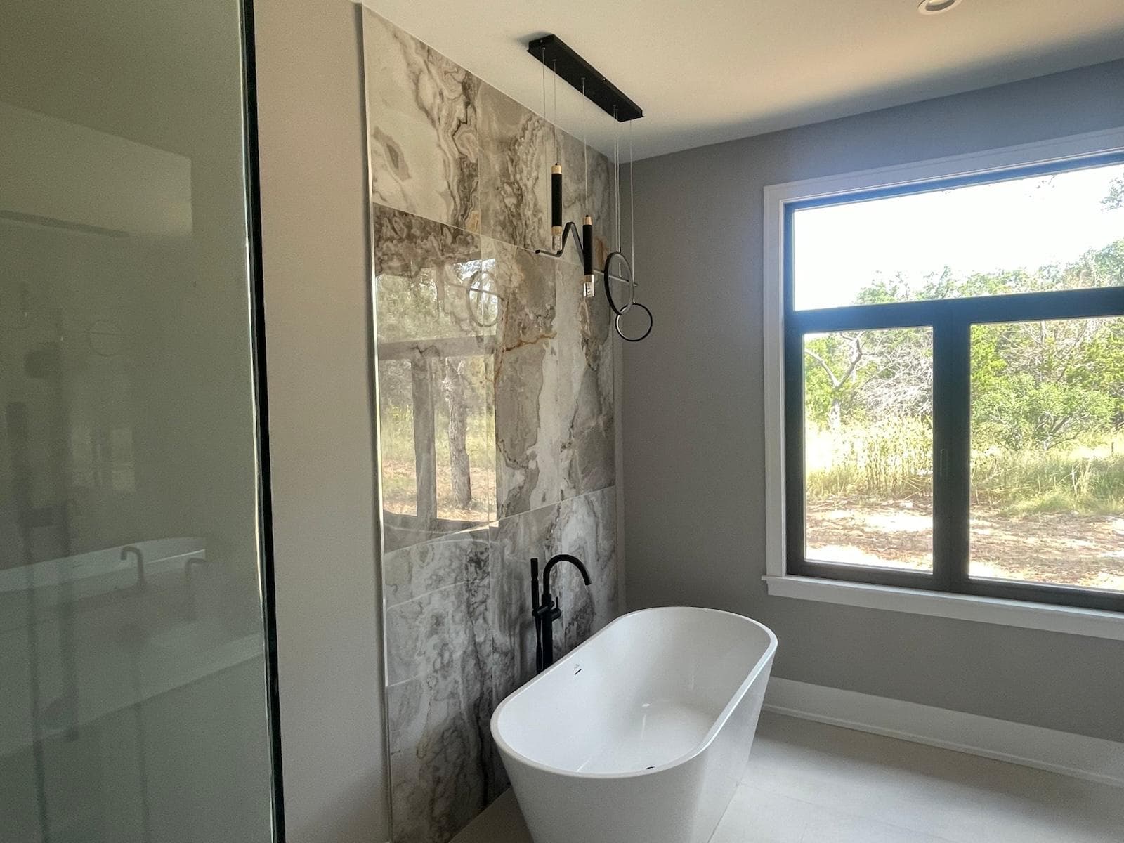 Freestanding bathtub positioned beneath a picture window with garden views — relaxing retreat