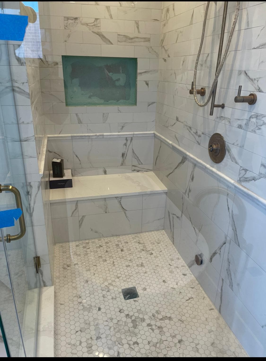 Oversized marble shower with built-in bench seat and niche shelving — spa-inspired bathroom