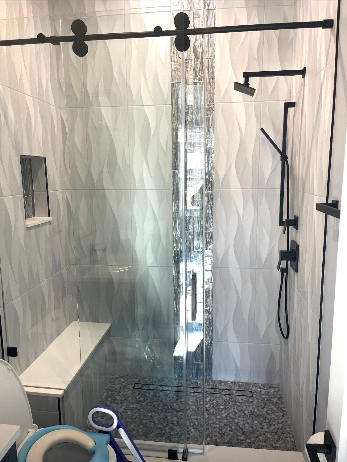 Custom wave-pattern tile shower with frameless glass enclosure — contemporary bath design