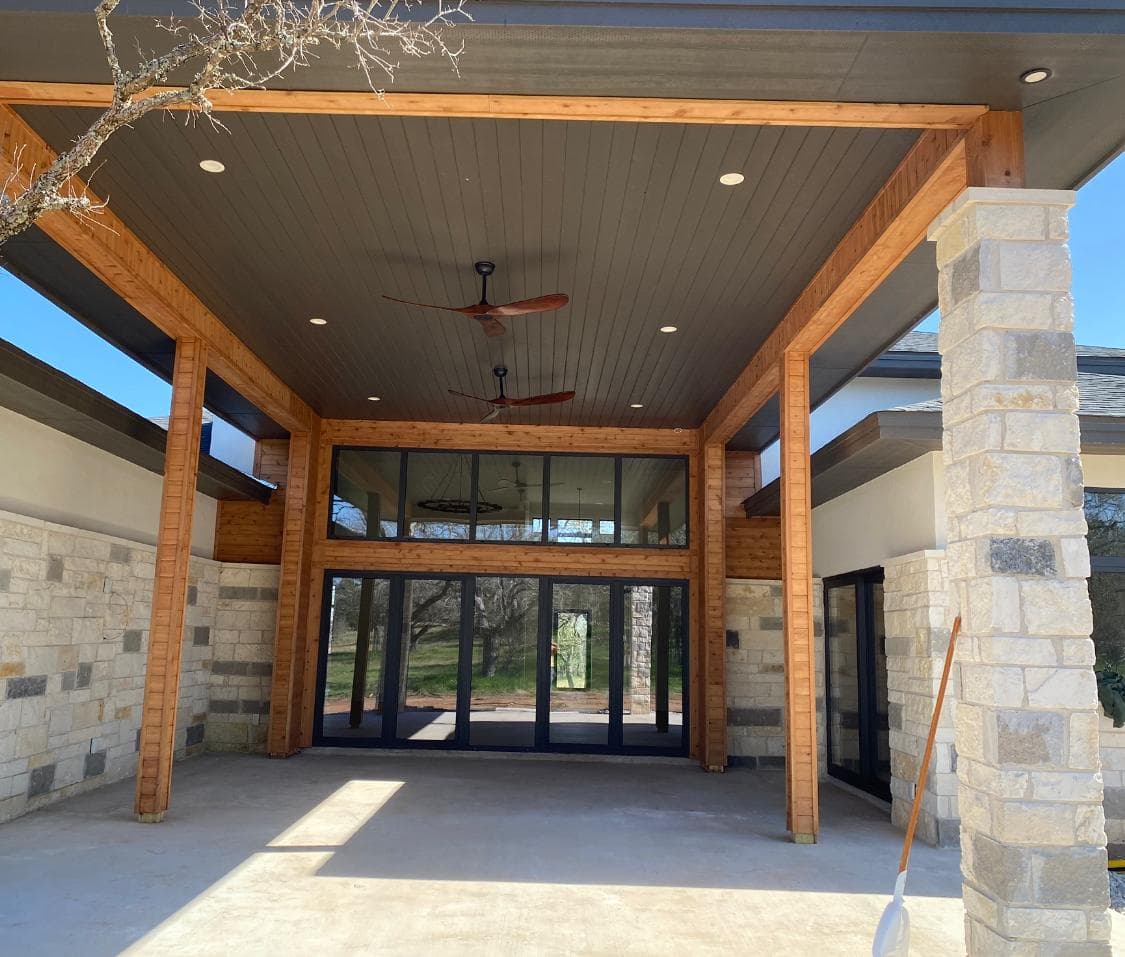 Covered patio with retractable glass doors for seamless indoor-outdoor living — Epic Homes