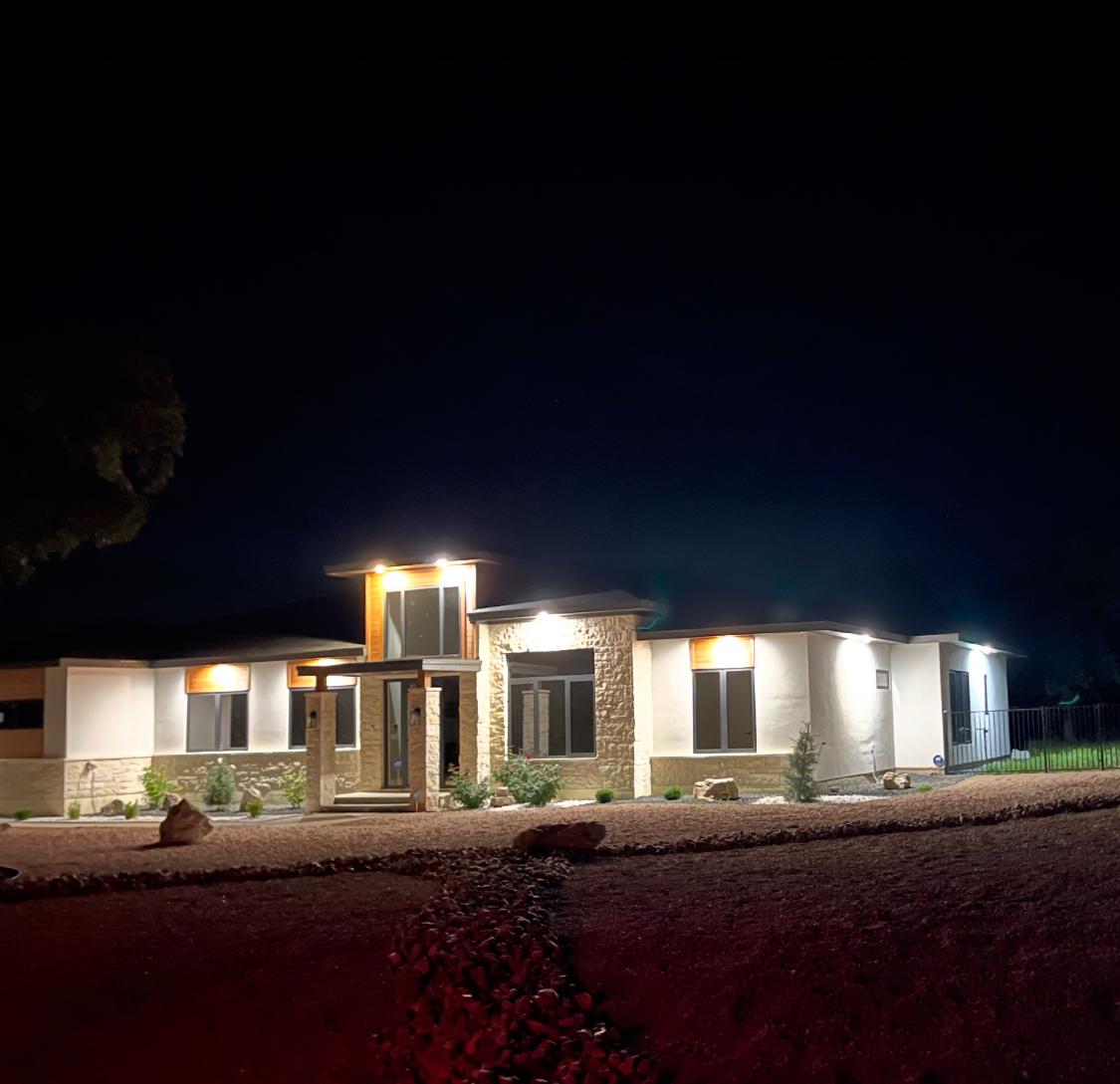 Epic Homes Construction — custom luxury home illuminated at dusk with professional landscape lighting, Bee Cave Texas